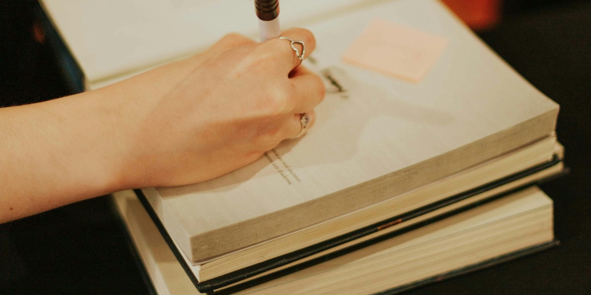 Persona escribiendo en un libro.
