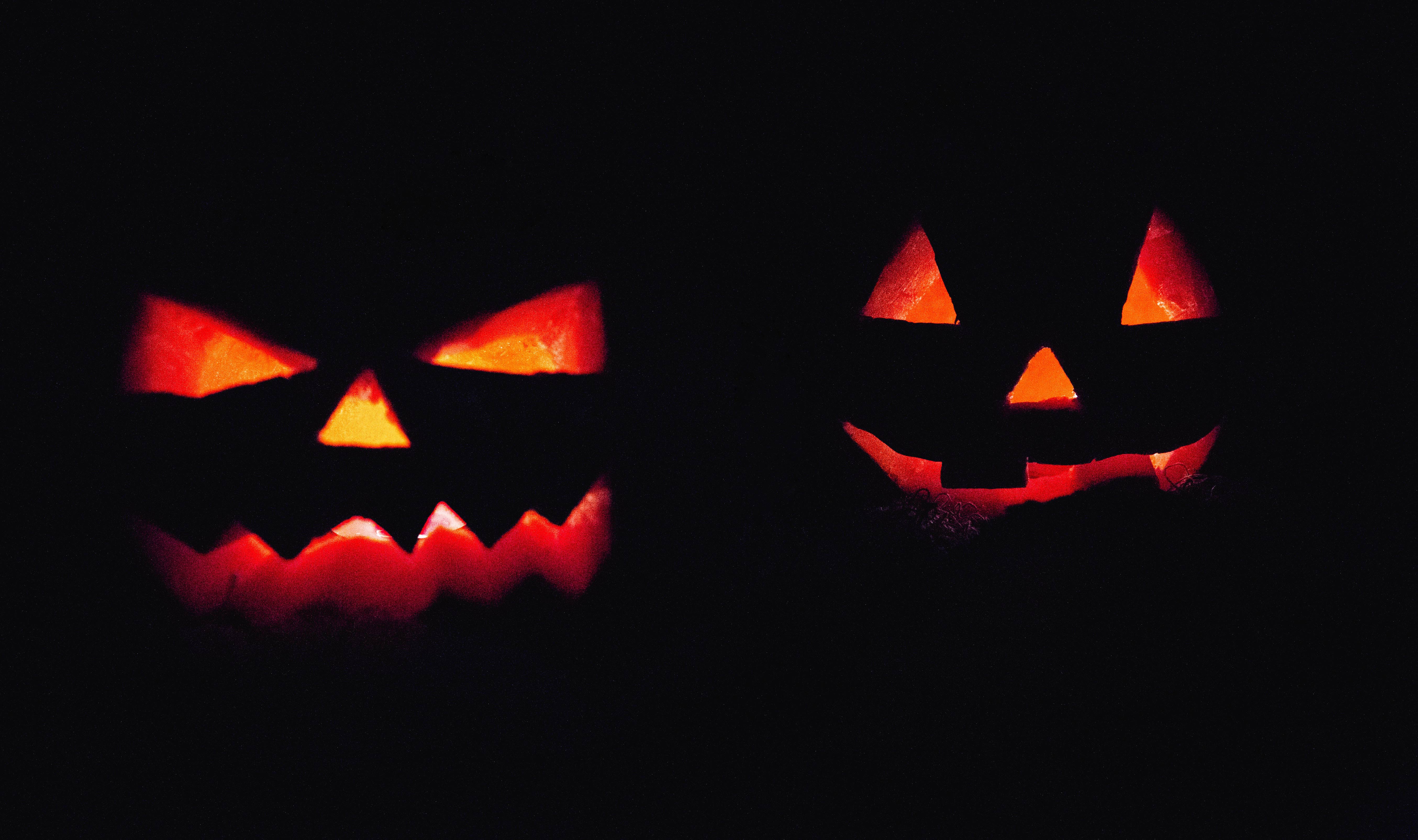 Dos calabazas de halloween con luz interior en un ambiente oscuro