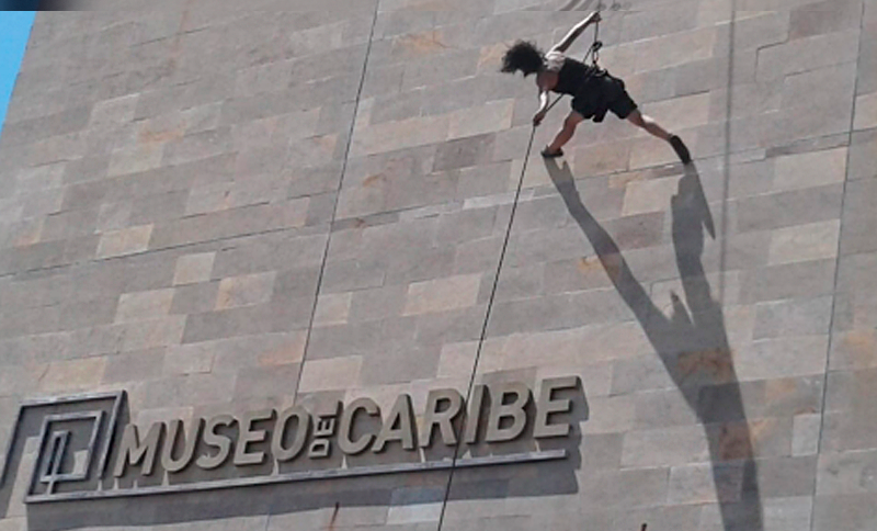 Persona caminando con un arnés por una parede de un museo