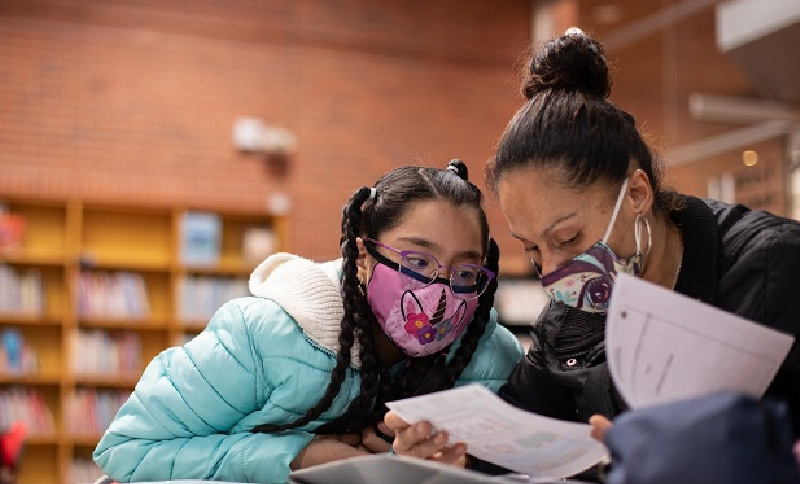 niña y mamá leyendo en una biblioteca