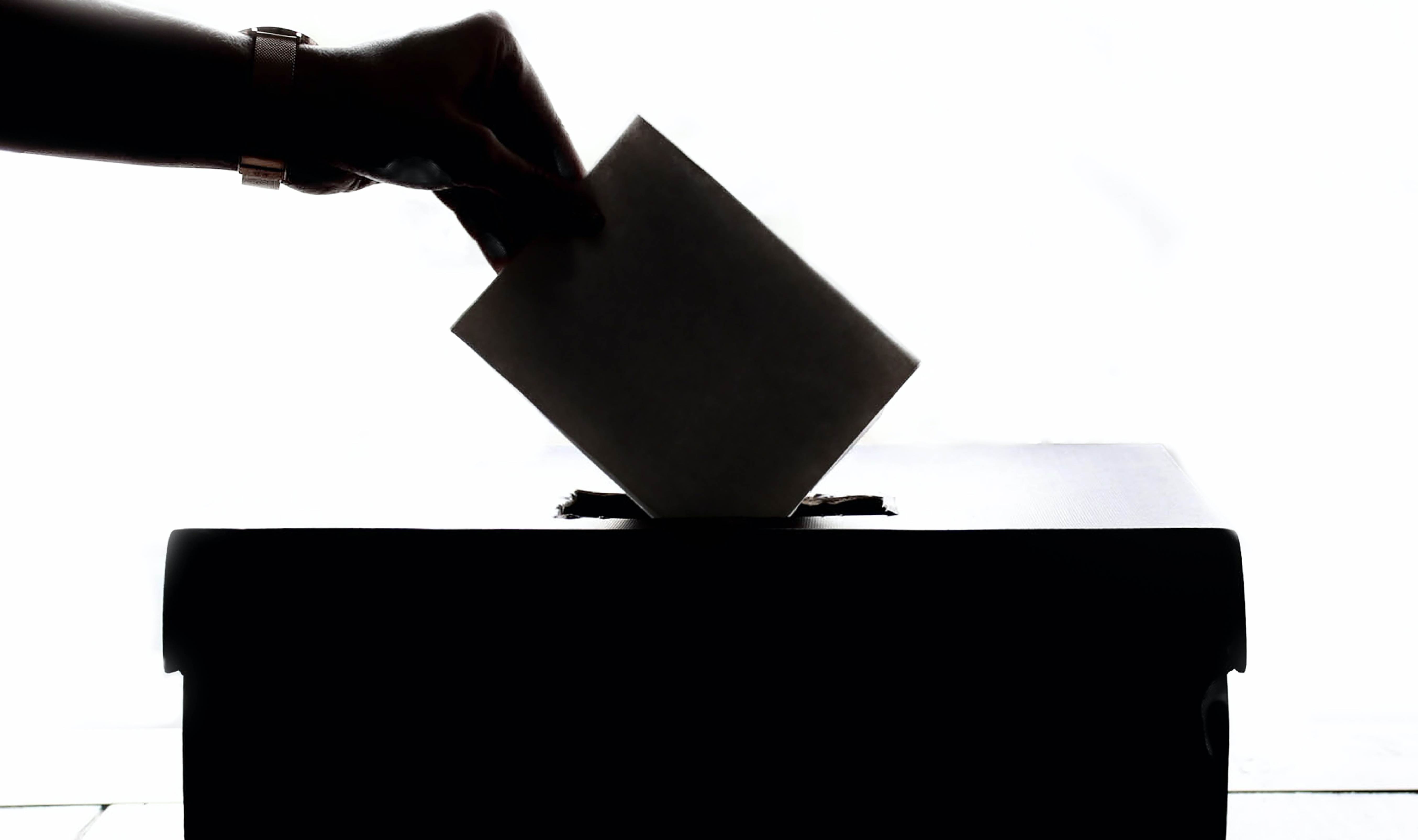 Silueta persona depositando su voto en una urna