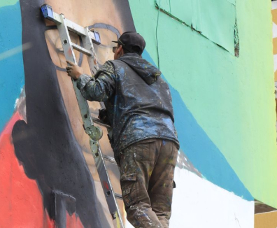 Artista visual pintando un mural en Ciudad Bolívar