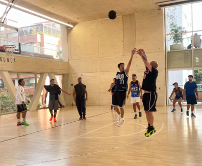 Fotografía de grupo de personas jugando baloncesto en la cancha de la arena polivalente