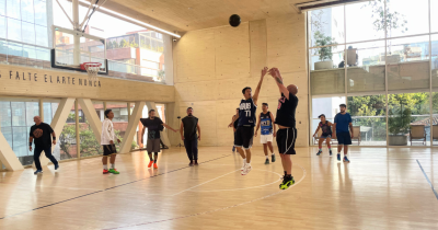Fotografía de grupo de personas jugando baloncesto en la cancha de la arena polivalente