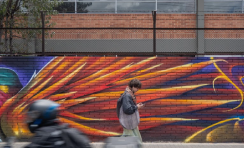 persona caminado en la calla con grafiti al fondo